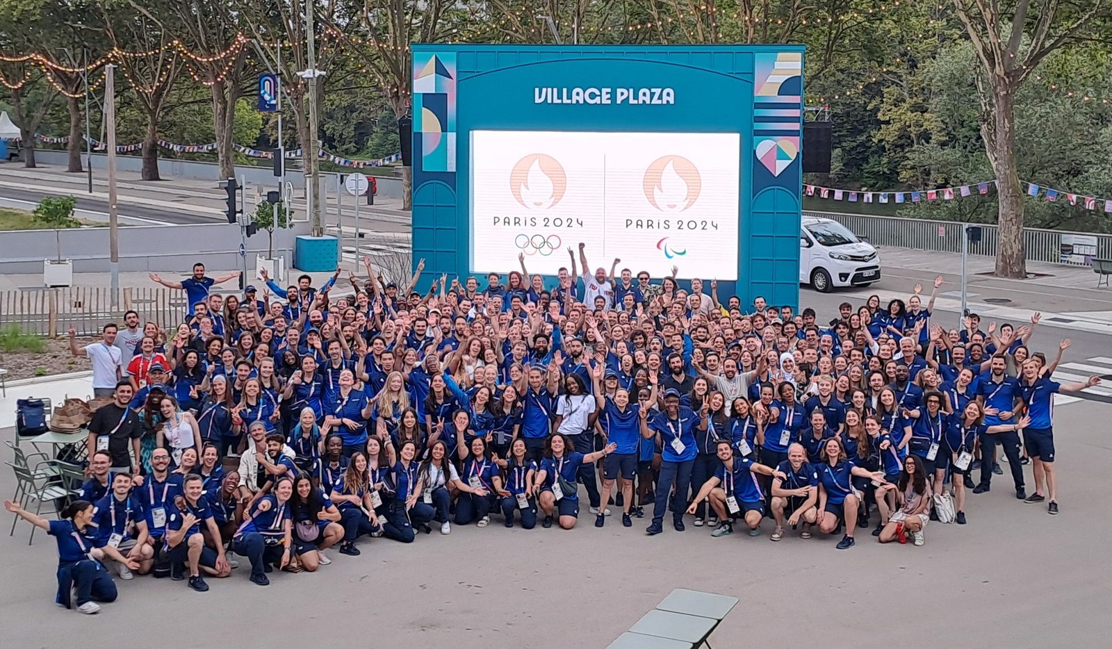 Plusieurs centaines de membres des équipes du village réunis sur la Village Plaza, devant l'écran Paris 2024