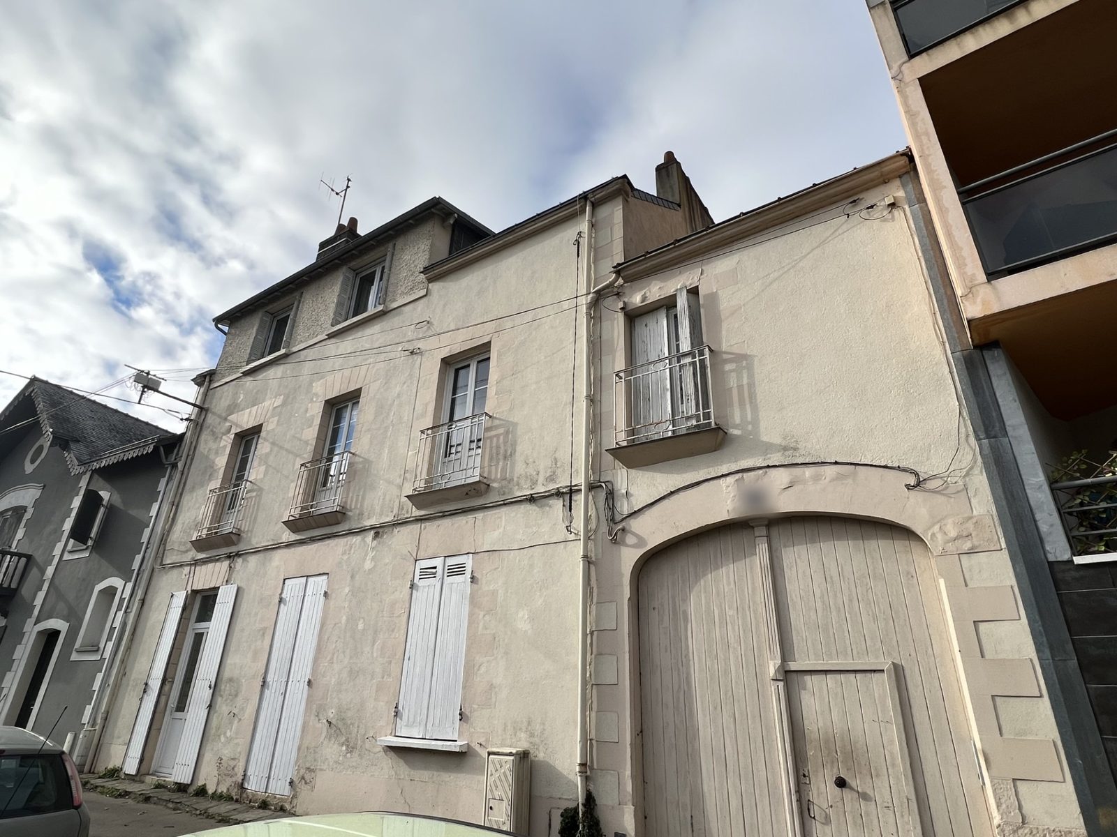 Façade d'un immeuble ancien en copropriété à Nantes, volets blancs et porte cochère en bois